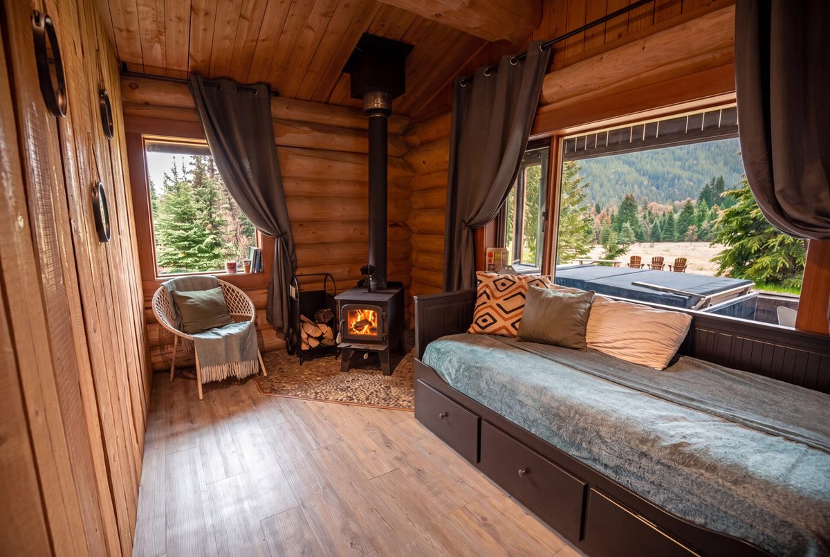 A cabin living room with log walls and forest views
