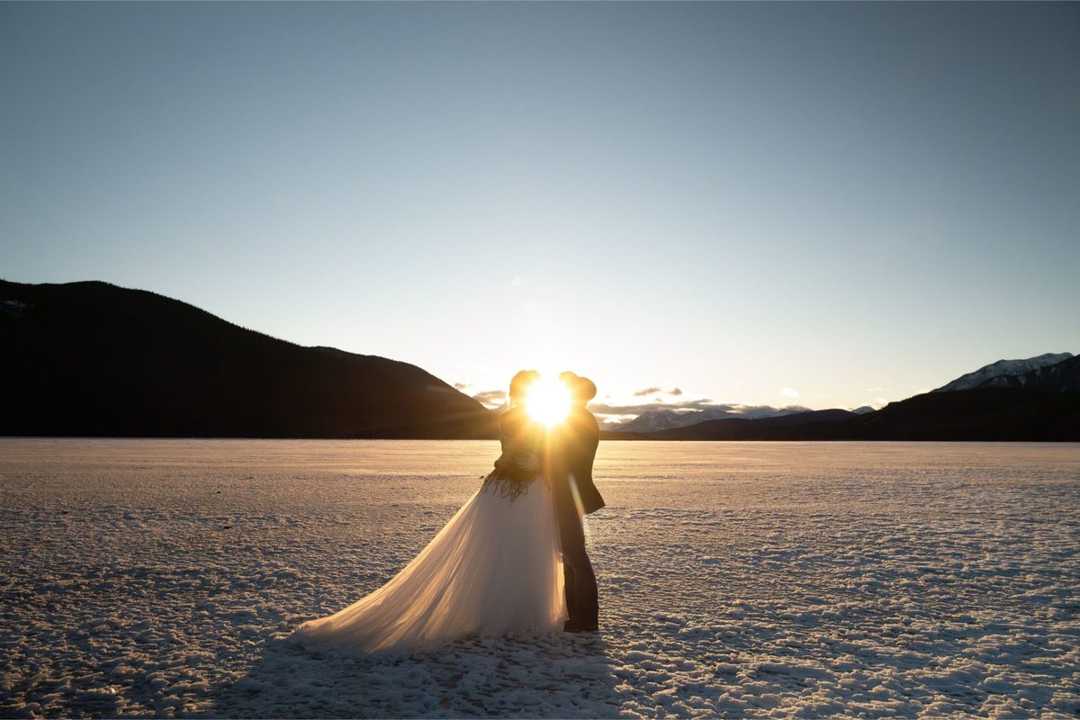 A couple kissing at sunset on frozen Rock Lake