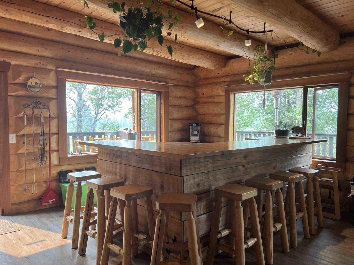 The hand-built log island bar with stools and mountain-view windows
