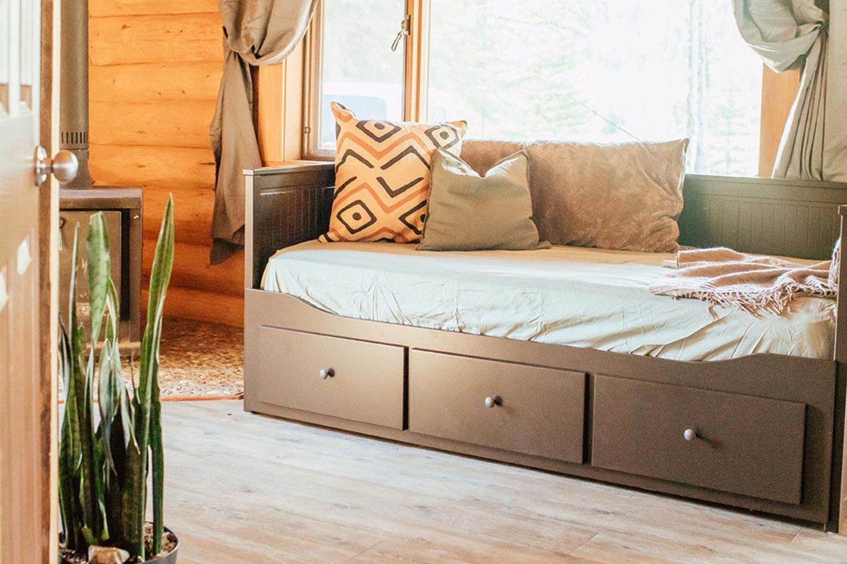 A king day bed beside forest windows