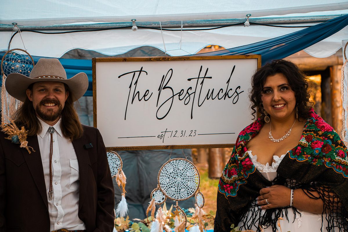 Cheanise and Brody Bestluck at their wedding sign reading The Bestlucks, established December 31, 2023