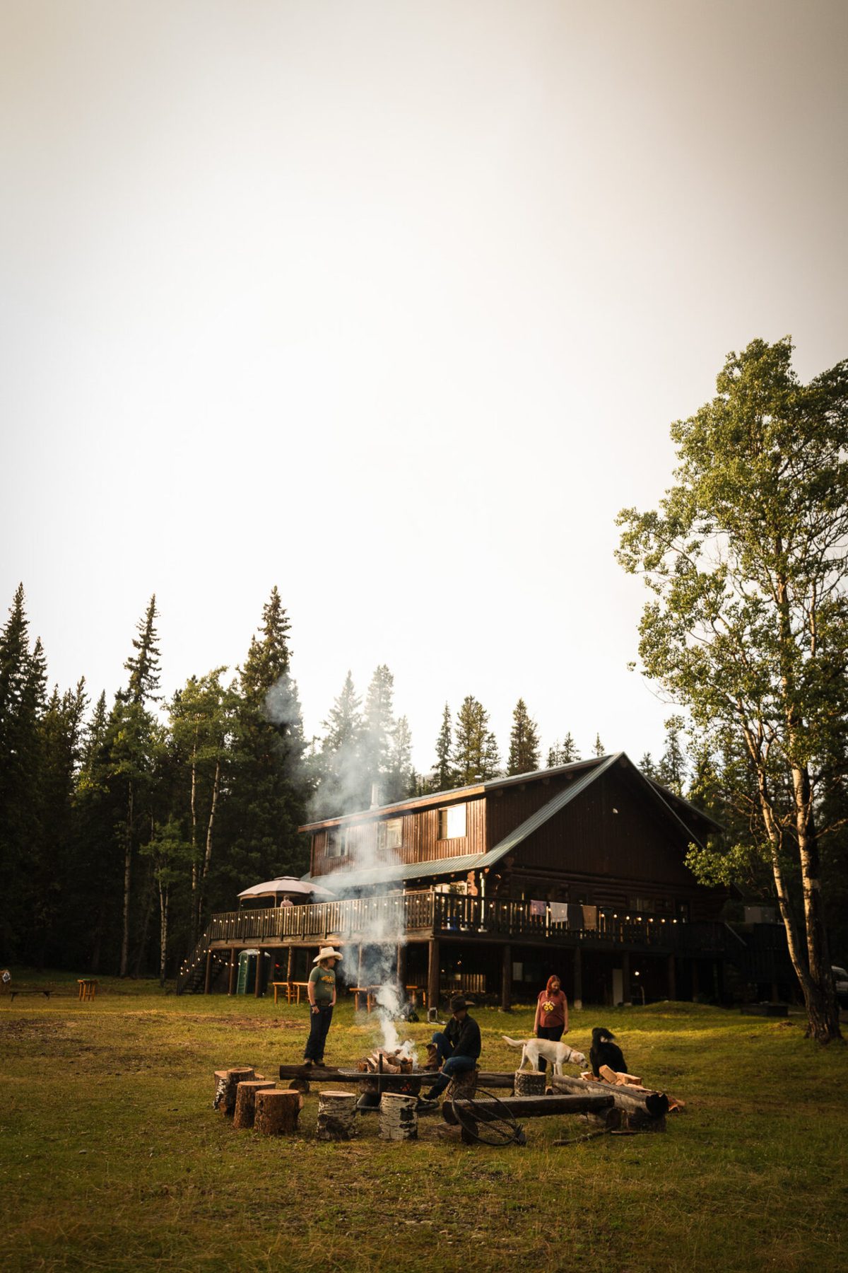 The lodge above the firepit meadow as evening smoke drifts through the trees